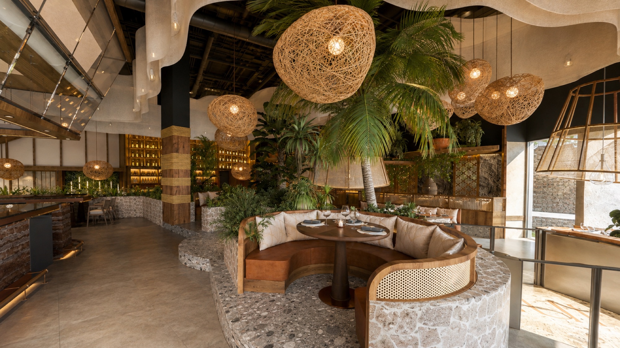 The MUI Supper Club dining room design, with woven pendant lights, a curved banquette and a tree at its center