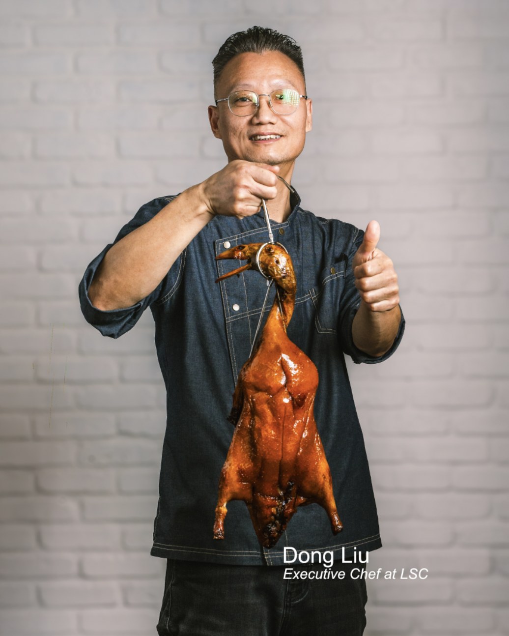 Chef Dong Liu, Executive Chef at Lao Sze Chuan, holding a whole roast duck