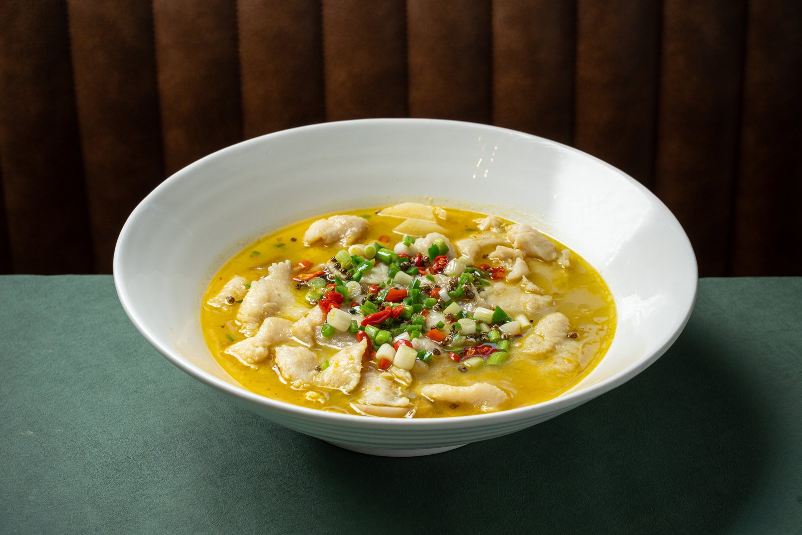 A wide bowl of fish fillets with green Sichuan peppercorns and chilies