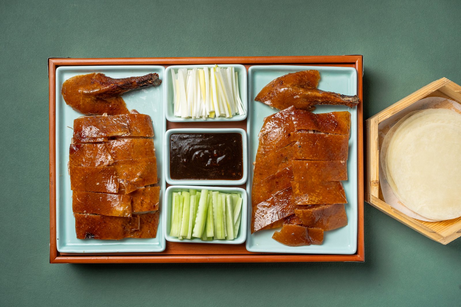 Golden Peking Duck sliced on a tray with pancakes, scallions, cucumber and sauce