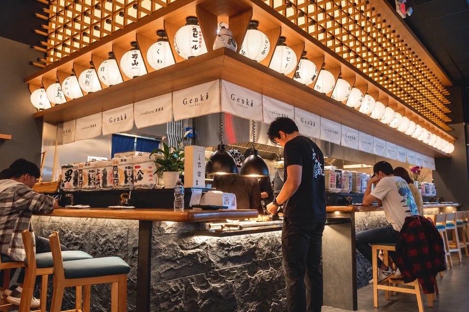La barra de cocina abierta de Genki Izakaya, bajo vigas de madera y faroles