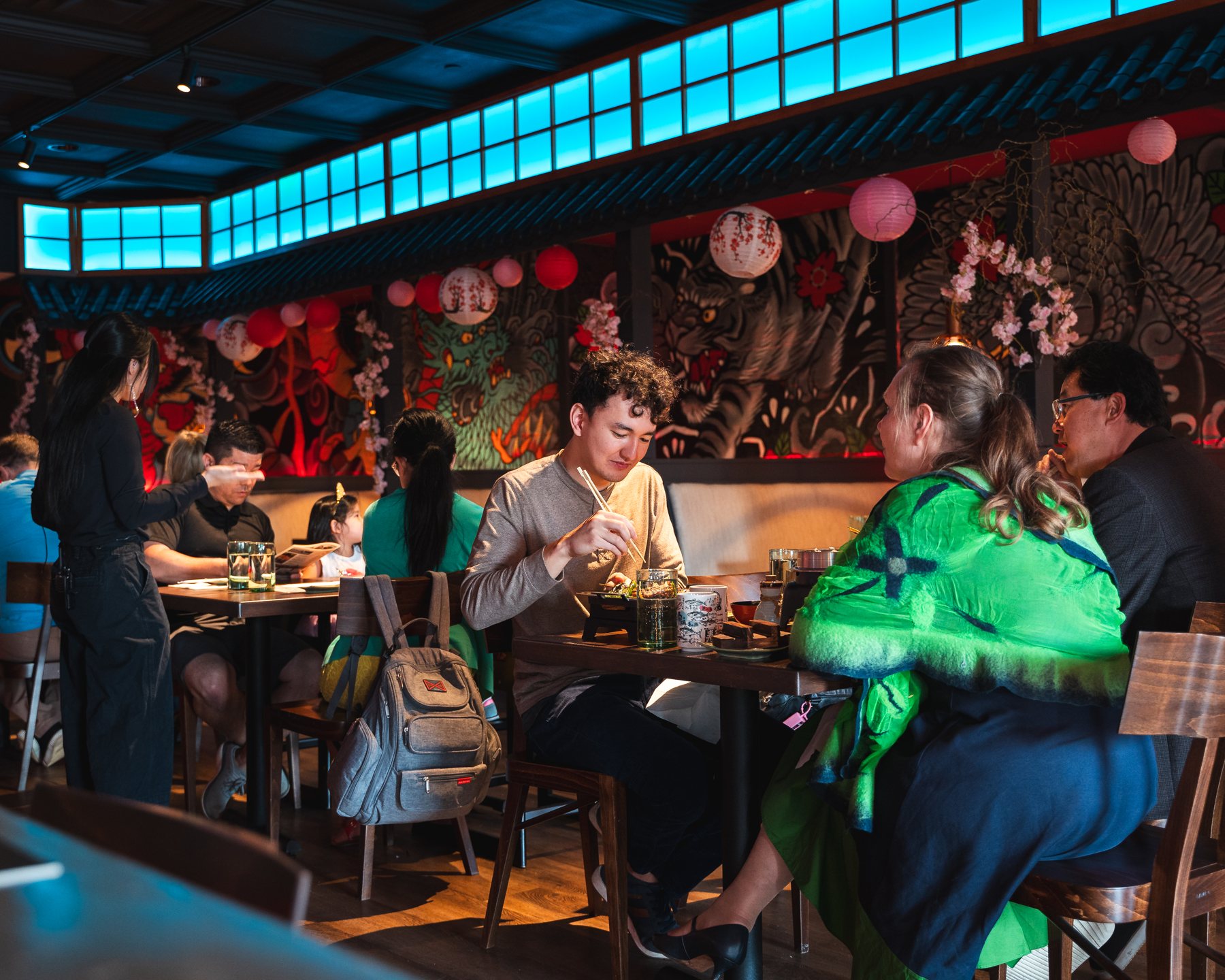 Comensales en el comedor iluminado con faroles de Sakaki Izakaya