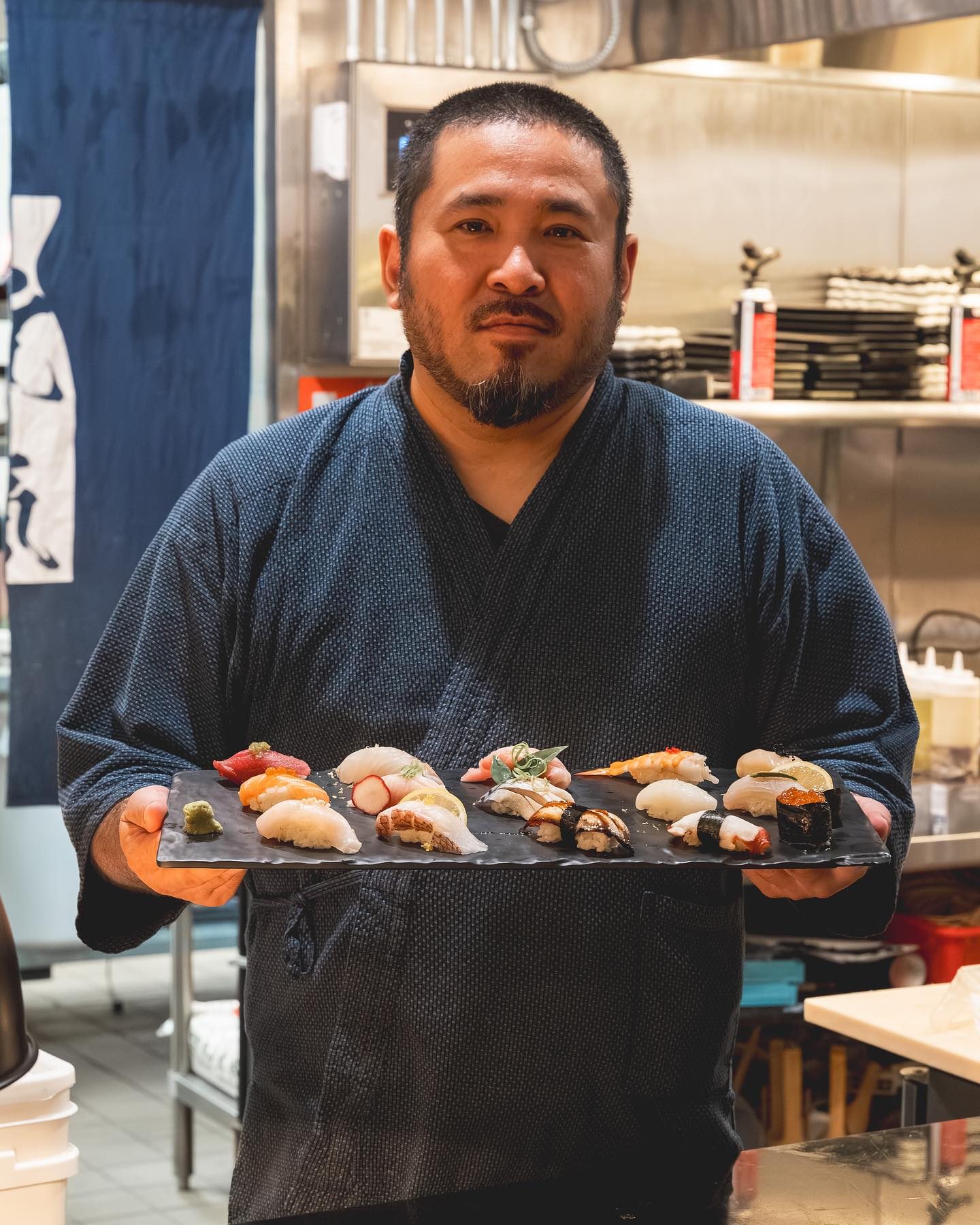 Chef Junzo Miyajima holding a slate board of nigiri sushi