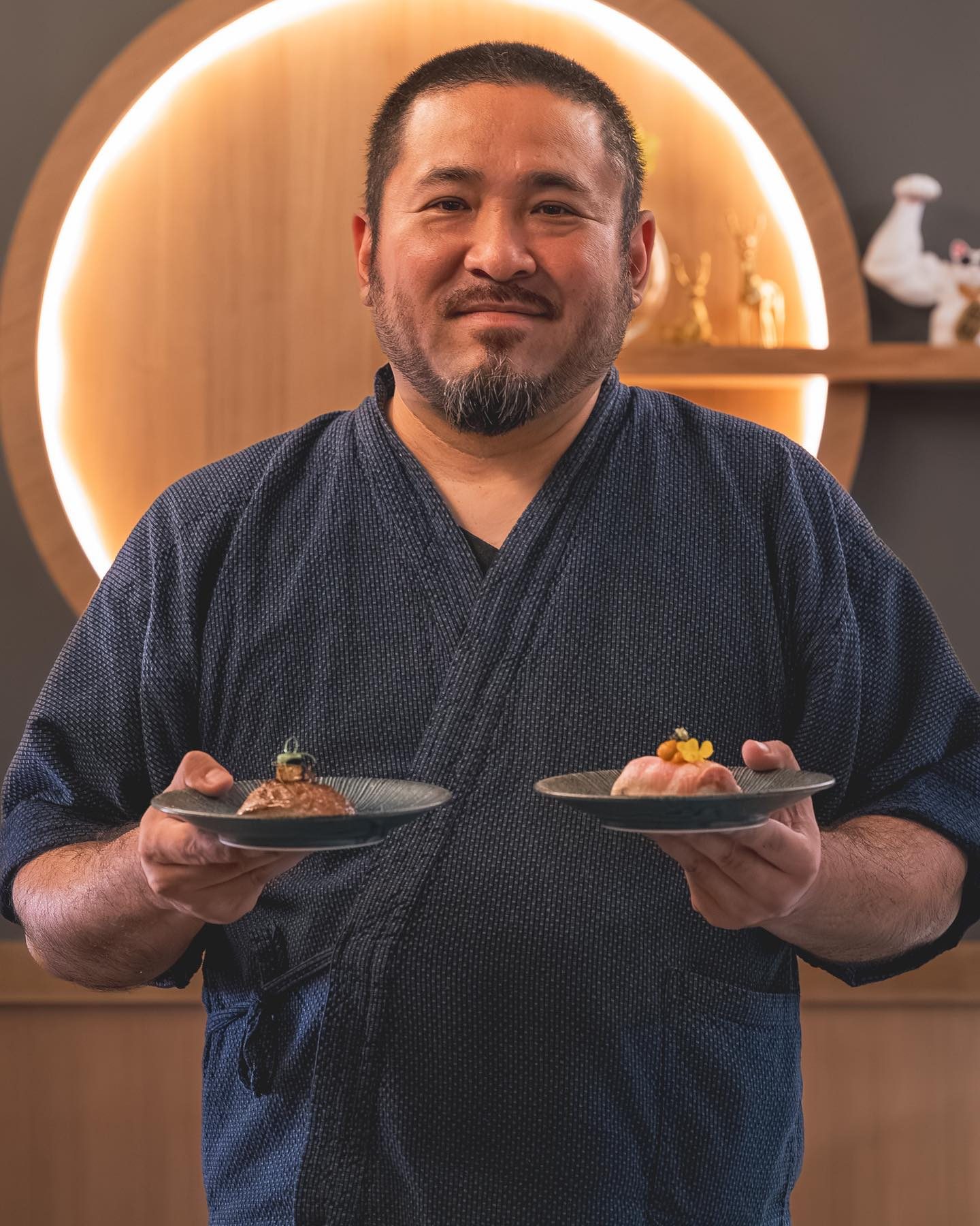 Chef Junzo Miyajima smiling with a plate in each hand