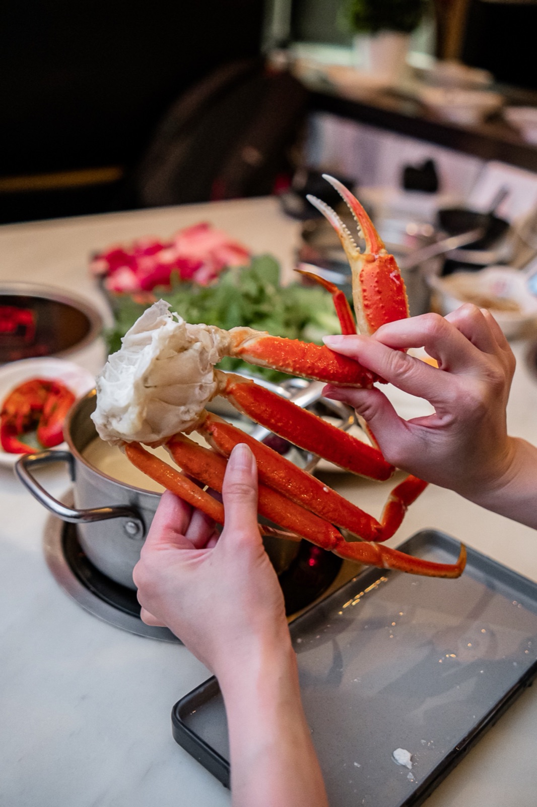 在 Urban Hot Pot,客人在一人一锅上方拿着煮好的雪蟹腿