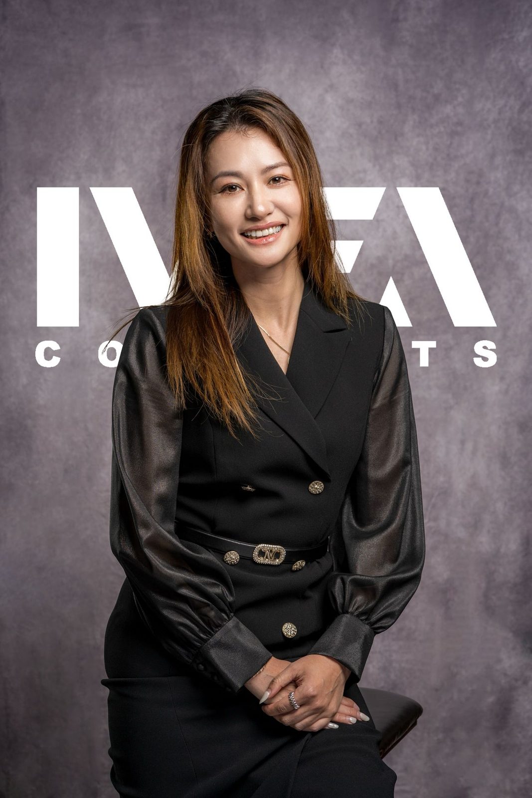 Vivian Zhu, IVEA co-founder and CFO, in a black blazer dress in front of the IVEA Concepts logo