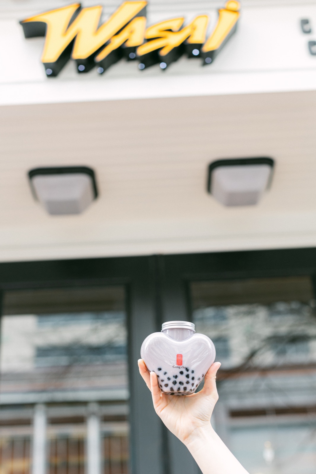 A Gong cha bubble tea held up under the Wasai sign