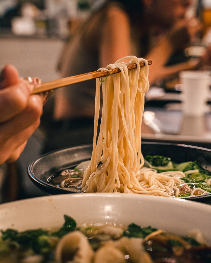 Thin hand-pulled noodles lifted from a bowl of noodle soup at Wasai